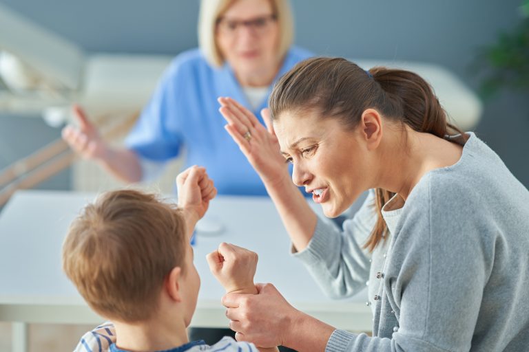 mother yelling at son with Oppositional Defiance Disorder while holding his wrist during therapy session